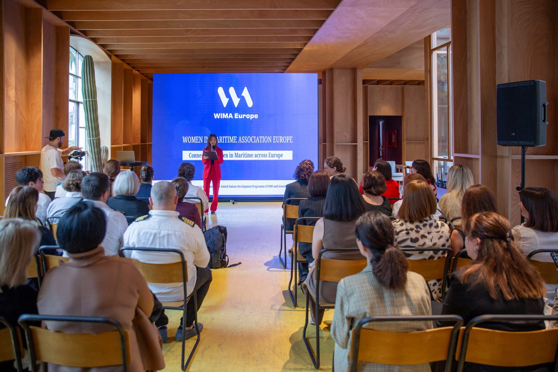 Women in maritime at a WIMA Europe event, listening to a speaker in front of the WIMA Europe screen